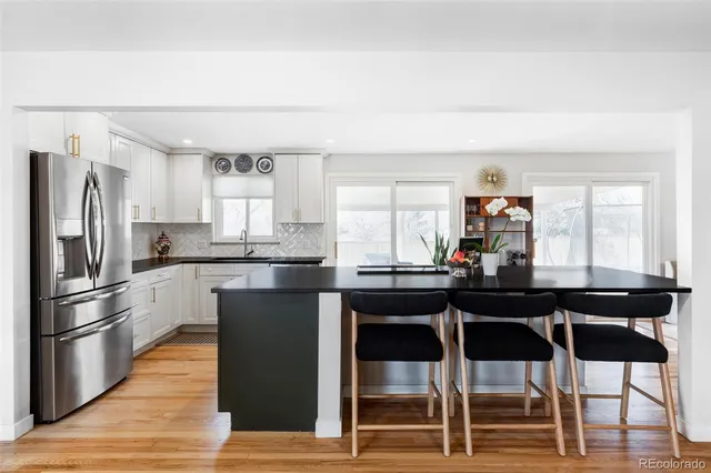 a kitchen with stainless steel appliances kitchen island granite countertop a table chairs a sink and a refrigerator