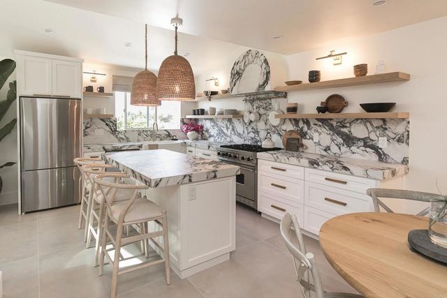 a kitchen with stainless steel appliances kitchen island granite countertop a sink stove and refrigerator