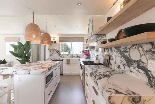 a kitchen that has a lot of white cabinets and stainless steel appliances