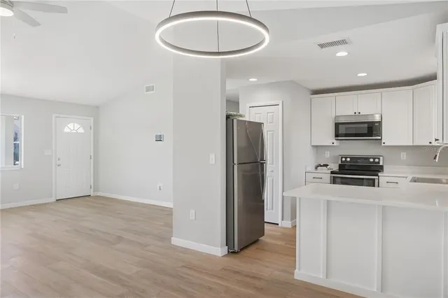 an empty room with wooden floor fan and windows
