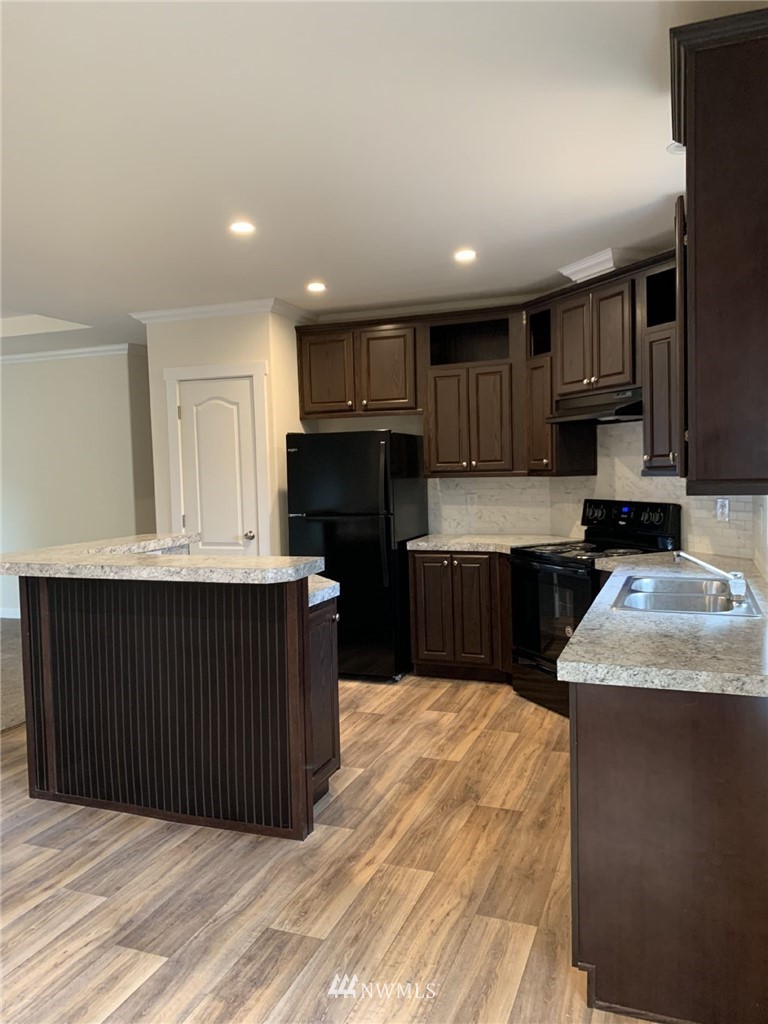 4590 Lake Terrell Road Ferndale, WA 98248 - Photo 8 of 25 a kitchen with kitchen island granite countertop wooden cabinets a refrigerator and a sink