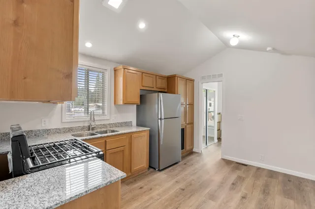 a kitchen with stainless steel appliances granite countertop a refrigerator stove and a sink