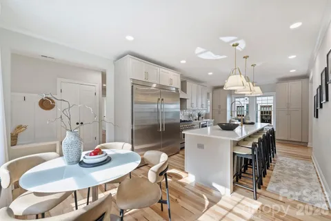 a kitchen with a dining table cabinets appliances and wooden floor