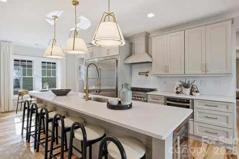 a kitchen with stainless steel appliances granite countertop a sink a stove and chairs