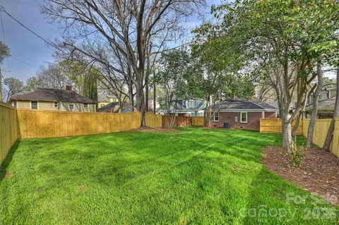 a view of a yard with a house and a large tree