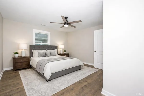 an empty room with wooden floor ceiling fan and windows