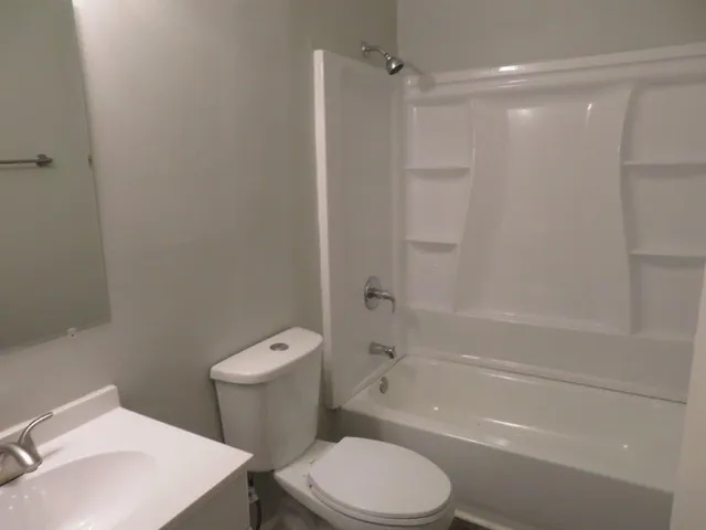a white toilet and tub sitting next to a bathroom sink