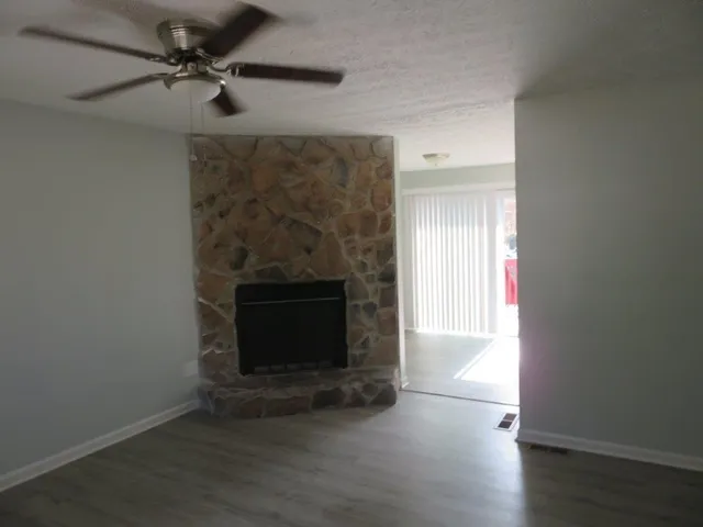 an empty room with wooden floor a fireplace and windows