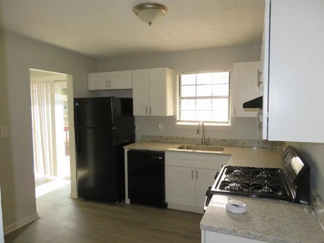 a kitchen with granite countertop a refrigerator stove and sink