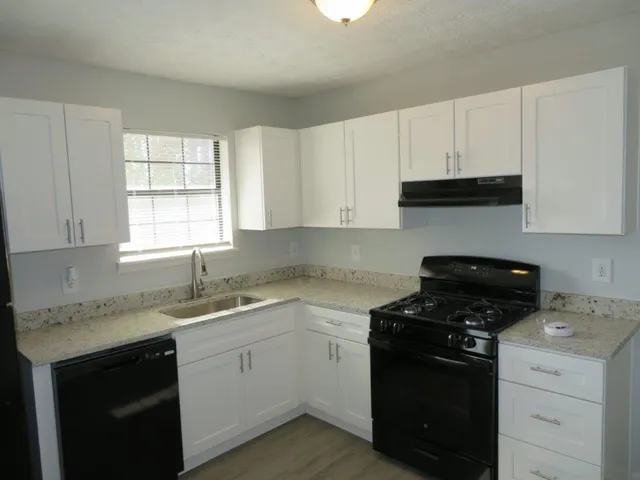 a kitchen with cabinets appliances a sink and a window