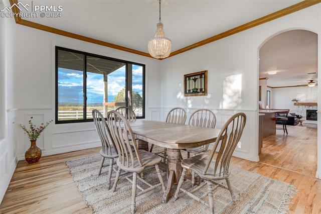 20880 Scott Road Peyton, CO 80831 - Photo 6 of 49 Dining space with light wood-type flooring, a stone fireplace, and ornamental molding