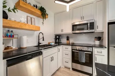 a kitchen with stainless steel appliances granite countertop a stove top oven a sink dishwasher a dining table and chairs with wooden floor