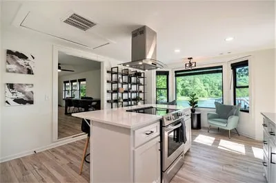 a large white kitchen with a stove a sink dishwasher and a fireplace with wooden floor