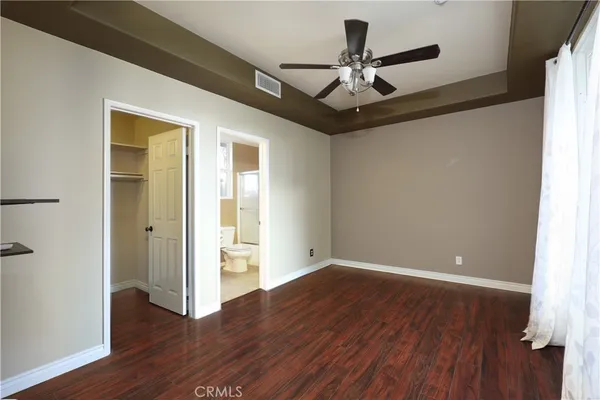 a view of an empty room with wooden floor and a ceiling fan