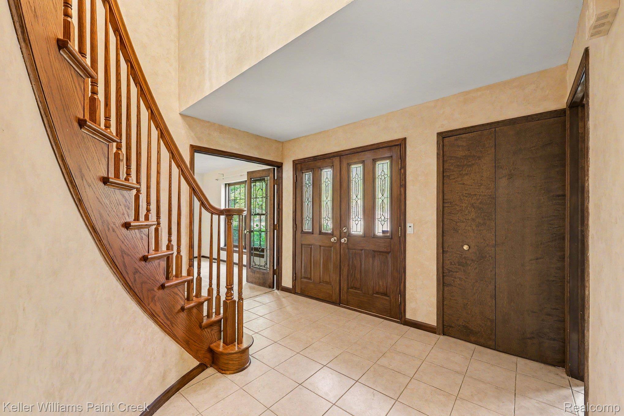 2717 Powderhorn Ridge Road Rochester, MI 48309 - Photo 6 of 48 Foyer featuring a curved wood staircase with turned balusters, tile flooring, and double entry doors with decorative glass panels
