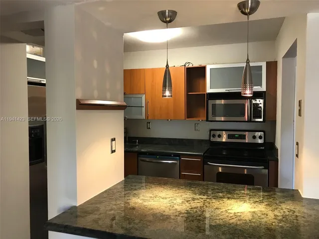 a kitchen with granite countertop a refrigerator and a stove top oven