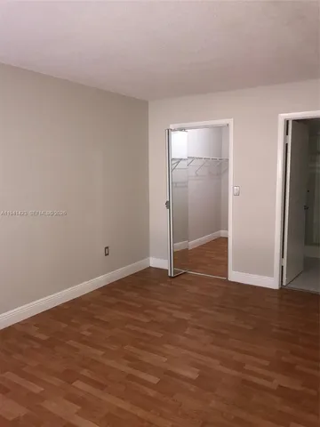 a view of an empty room with wooden floor and closet