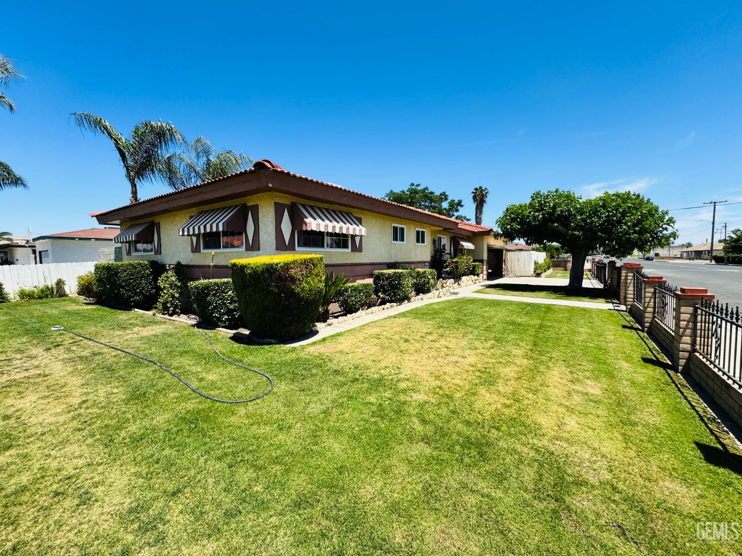 Undisclosed Address Delano, CA 93215 - Photo 13 of 14 a yellow house with a big yard and large trees