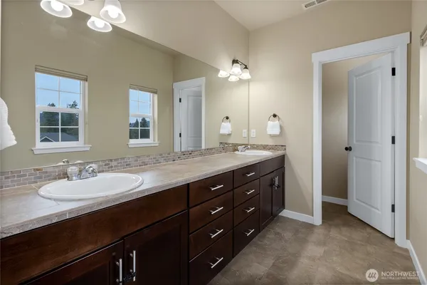 a bathroom with a granite countertop double vanity sink and a mirror