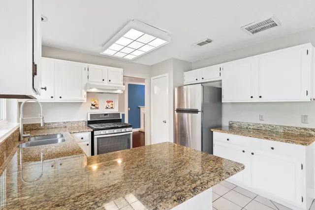 a kitchen with white cabinets and refrigerator