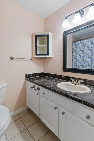 a bathroom with a granite countertop toilet and a sink