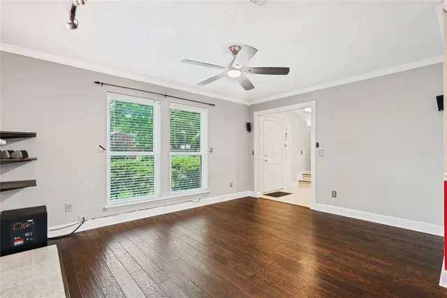 a view of an empty room with wooden floor and a window
