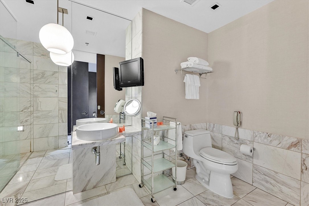 4381 West Flamingo Road, Unit 1609 Las Vegas, NV 89103 - Photo 13 of 27 Bathroom with toilet, tiled shower, and tile walls