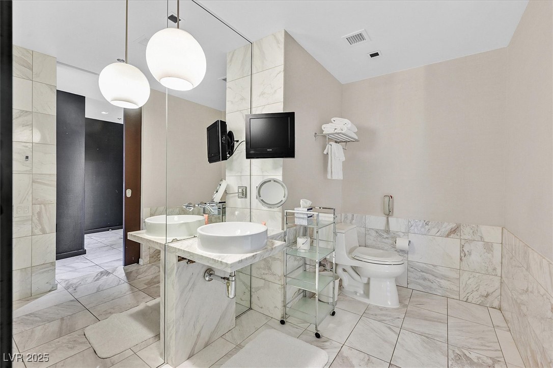 4381 West Flamingo Road, Unit 1609 Las Vegas, NV 89103 - Photo 15 of 27 Bathroom featuring marble finish floor, a sink, tile walls, and visible vents