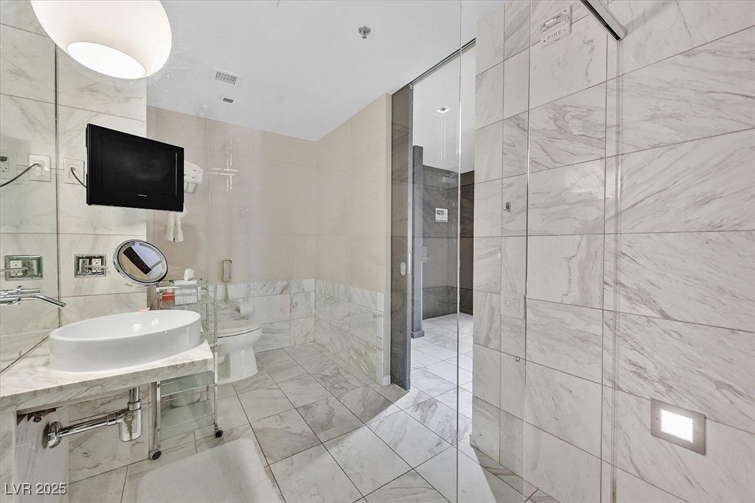 4381 West Flamingo Road, Unit 1609 Las Vegas, NV 89103 - Photo 16 of 27 Bathroom with tile walls, visible vents, a sink, and toilet