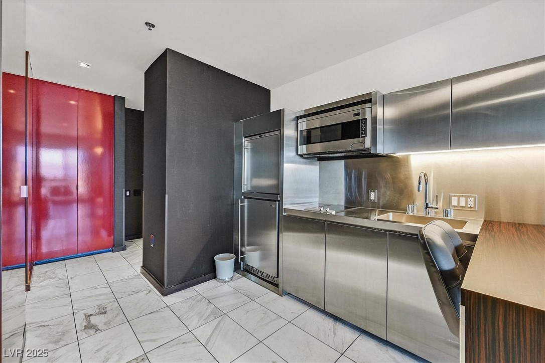 4381 West Flamingo Road, Unit 1609 Las Vegas, NV 89103 - Photo 18 of 27 Kitchen with marble finish floor, modern cabinets, stainless steel microwave, a sink, and black electric stovetop