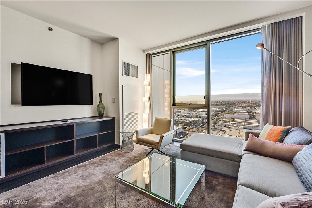4381 West Flamingo Road, Unit 1609 Las Vegas, NV 89103 - Photo 6 of 27 Carpeted living area featuring visible vents and a wall of windows