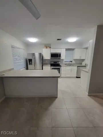 a large kitchen with stainless steel appliances a stove a sink a microwave and a refrigerator