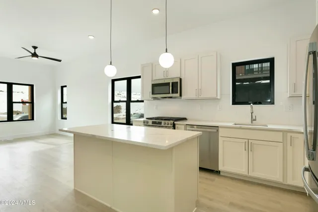 a kitchen with stainless steel appliances granite countertop a sink a stove and a wooden floors