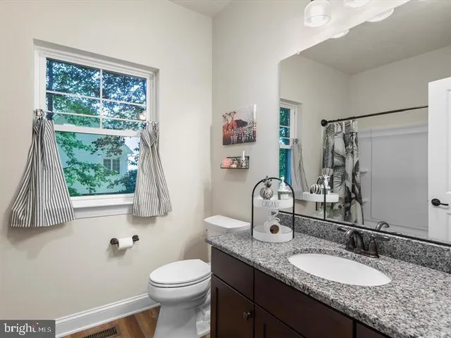 a bathroom with a granite countertop sink toilet and a mirror