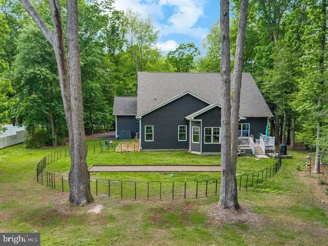 a view of house with a big yard and large trees