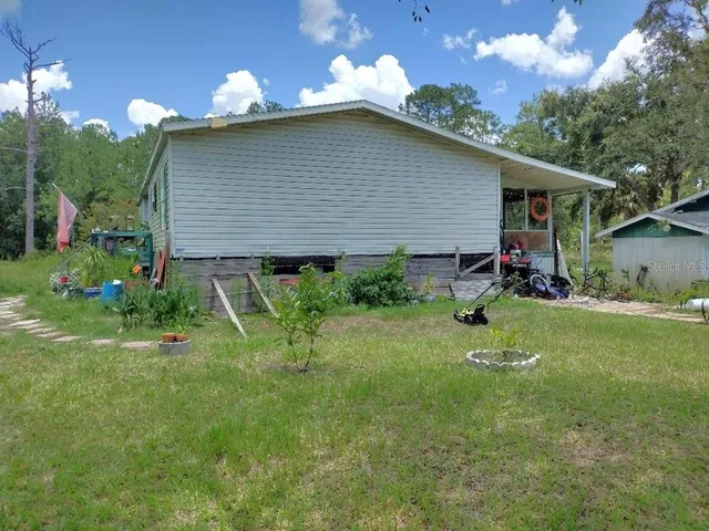 a backyard of a house with table and chairs plants and large trees
