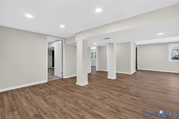an empty room with windows a fireplace and wooden floor