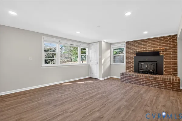 a view of an empty room with wooden floor fireplace and a window