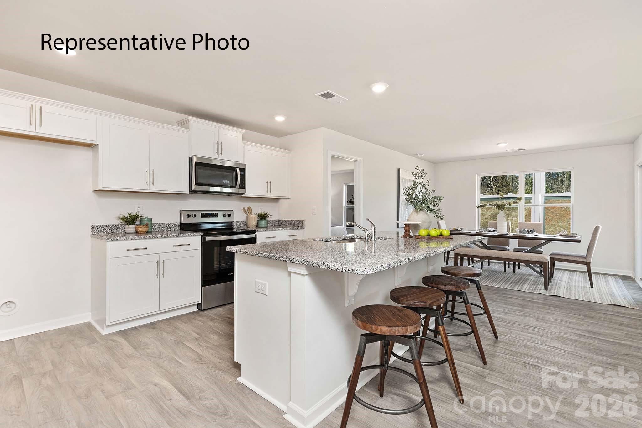 2696 Goose Fair Road Maiden, NC 28650 - Photo 13 of 21 a kitchen with white cabinets a sink a stove a dining table and chairs