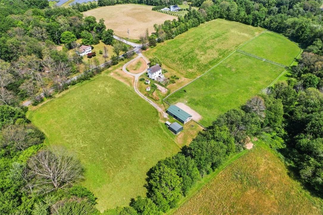 an aerial view of a residential houses with outdoor space and trees all around