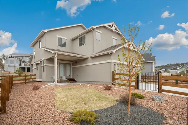 a view of a white house with large windows and wooden fence