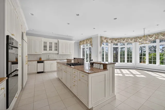 a large white kitchen with cabinets a sink a window and stainless steel appliances
