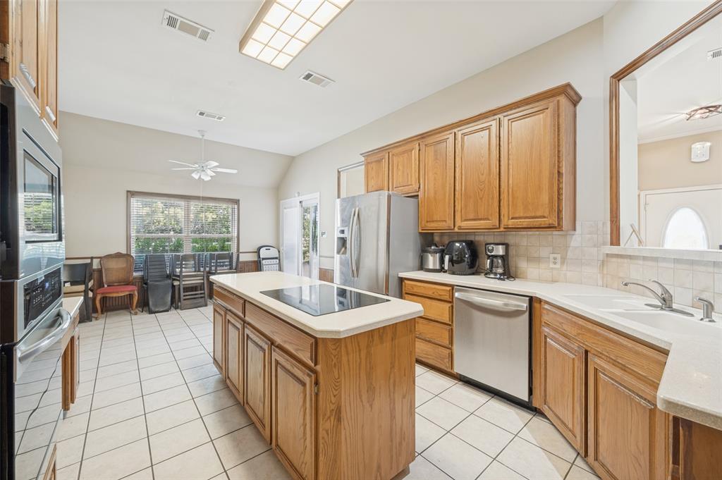 1601 East Blackjack Road East Pilot Point, TX 76258 - Photo 7 of 30 Kitchen featuring wood cabinetry, stainless steel appliances, a central island with cooktop, and tile flooring
