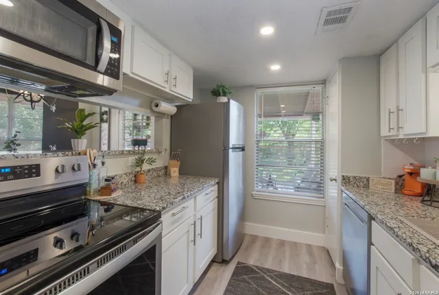 a kitchen with stainless steel appliances granite countertop a refrigerator and a stove