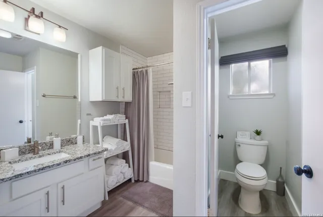 a bathroom with a granite countertop toilet a sink and a mirror