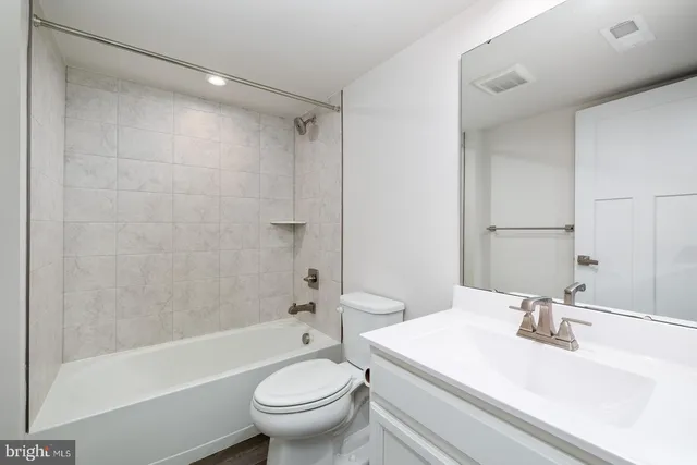 a kitchen with stainless steel appliances kitchen island granite countertop a refrigerator a stove a kitchen island with chairs and white cabinets