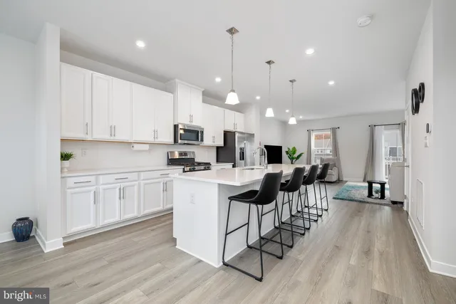 a large white kitchen with wooden floor and stainless steel appliances