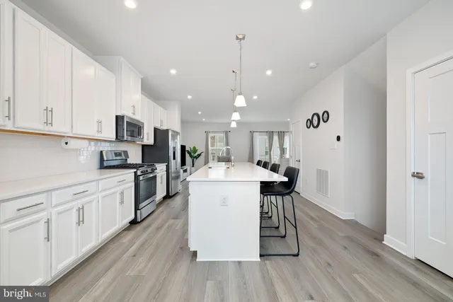 a large kitchen with stainless steel appliances kitchen island a large counter space a sink and a wooden floor