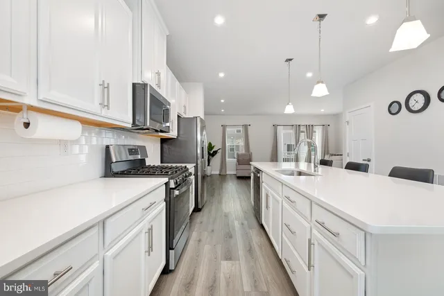 a large kitchen with lots of counter space a sink appliances and cabinets