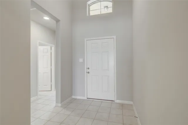 an empty room with chandelier fan and windows